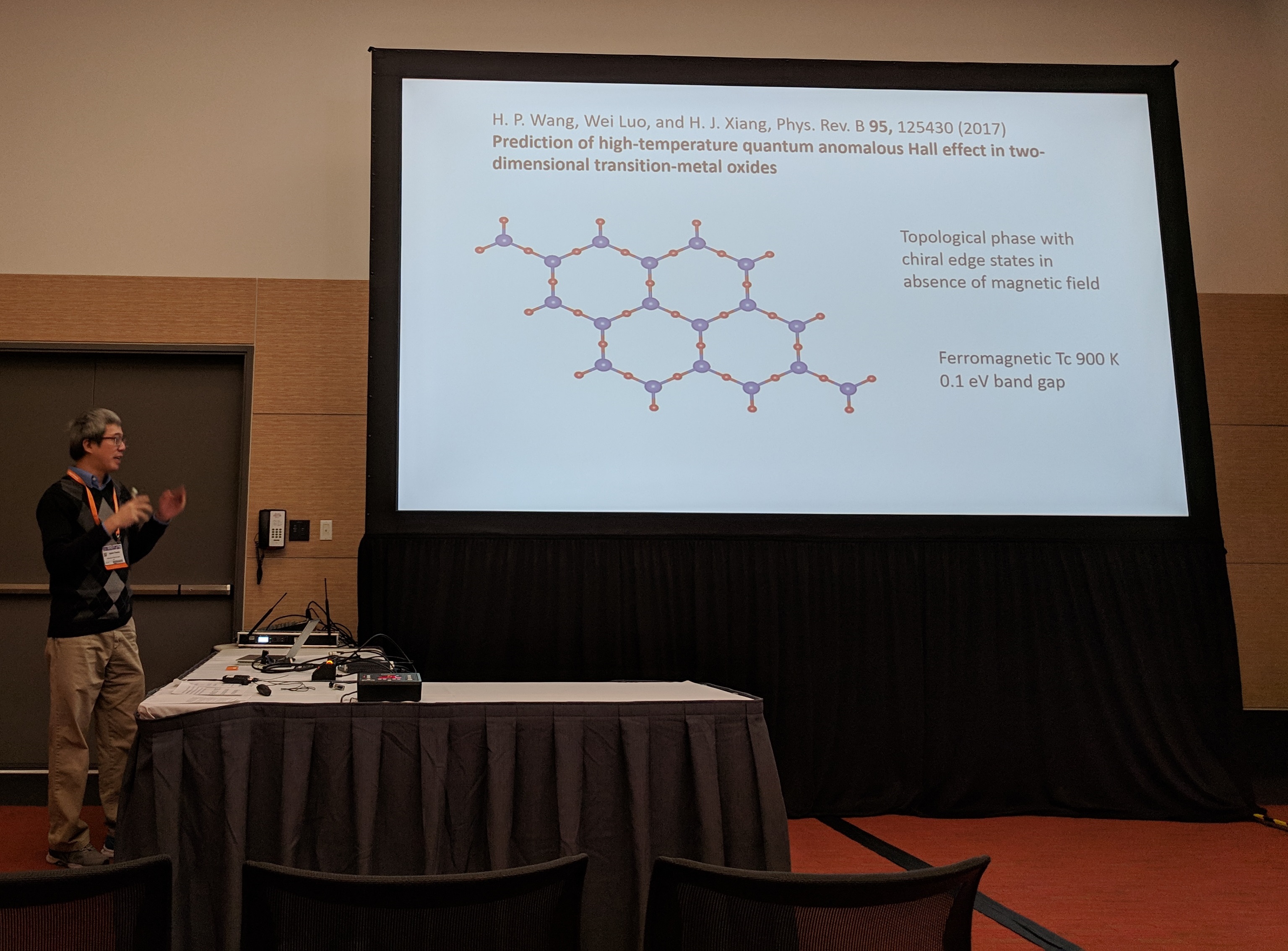 Agham next to a projection screen with one of the slides from his talk.